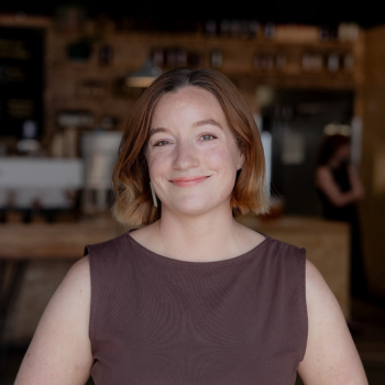 Woman with short hair smiling in café setting with blurred background
